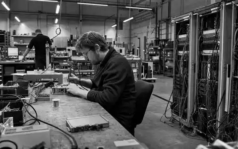 Kontron AG (DE0006053952) dokumentiert in Schwarzweiß einen Ingenieur beim Löten eines Embedded-Computer-Moduls in der Werkstatt - Foto: THN