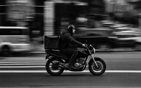 Domino's Pizza US25754A1016 Lieferkurier auf Motorrad in dokumentarischer Schwarzweiß-Reportage einer belebten Stadtstraße - Foto: THN