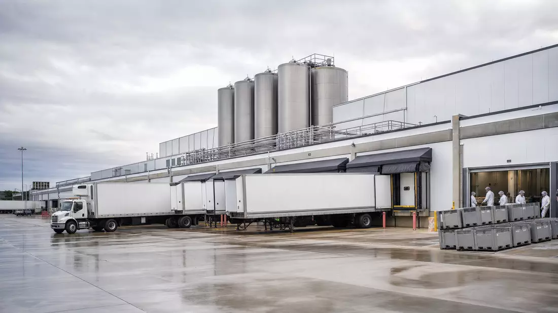 Fleischverarbeitungsanlage mit LKWs und Silos im industriellen Tageslicht