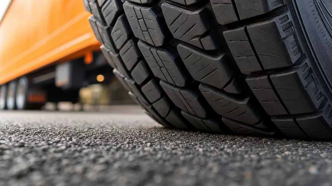 Extreme Nahaufnahme eines LKW-Reifenprofils auf Asphalt mit unscharfem Hintergrund