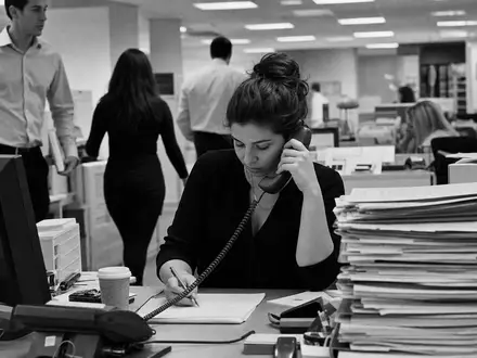 Robert Half Inc. (ISIN US7703231032) dokumentiert Schwarzweiß-Reportage einer Recruiterin am Telefon im belebten Vermittlungsbüro - Foto: THN