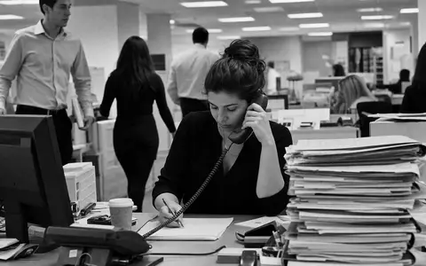 Robert Half Inc. (ISIN US7703231032) dokumentiert Schwarzweiß-Reportage einer Recruiterin am Telefon im belebten Vermittlungsbüro - Foto: THN