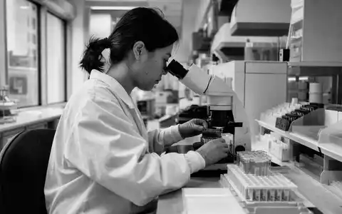 Schwarzweiß-Reportage dokumentiert Diagnostik-Alltag bei Revvity Inc. (ISIN US76155R1086) mit Mikroskop und Probenröhrchen - Foto: THN