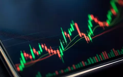 Robinhood Markets US7707031024 zeigt eine extreme Makroaufnahme eines Smartphone-Bildschirms mit leuchtenden grün-roten Candlestick-Kursdaten heute - Foto: THN