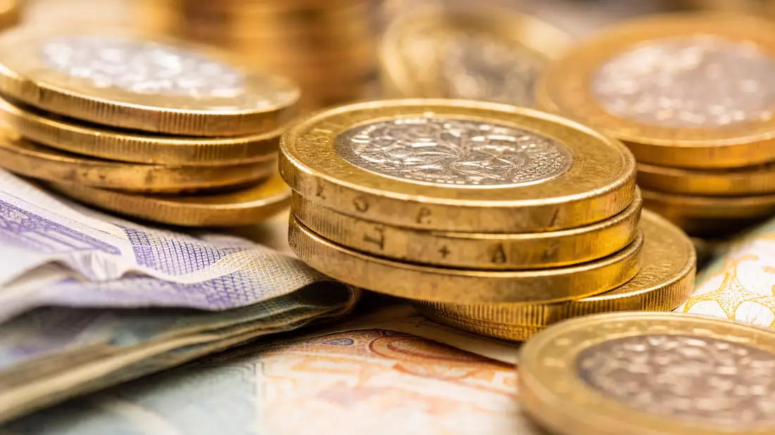 Extreme Makroaufnahme britischer Münzen und Banknoten in warmen Gold- und Bronzetönen