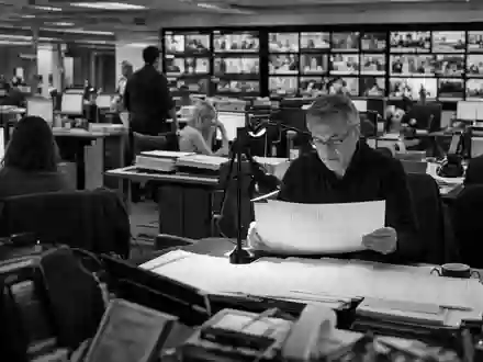 News Corp (Class A) US65249B1098: Schwarzweiß-Reportagefoto einer generischen belebten Nachrichtenredaktion mit Journalisten - Foto: THN