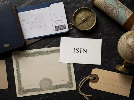 Booking Holdings Inc. Flatlay mit Reiseutensilien, Aktienzertifikat, Kompass und ISIN-Karte auf Marmor US09857L1089 - Foto: THN