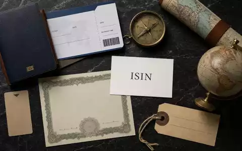 Booking Holdings Inc. Flatlay mit Reiseutensilien, Aktienzertifikat, Kompass und ISIN-Karte auf Marmor US09857L1089 - Foto: THN