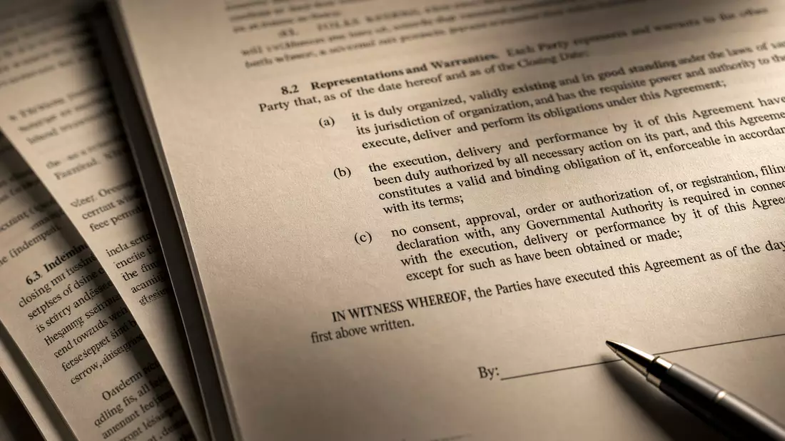 Extreme Nahaufnahme eines Finanzvertrags mit Stift auf Unterschriftslinie, warmes Licht