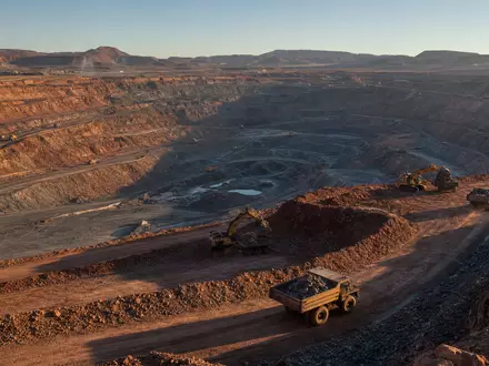 Glencore plc (ISIN JE00B4T3BW64) betreibt riesige Kupfertagebauten mit schweren Muldenkippern in staubiger Bergbaulandschaft - Foto: THN