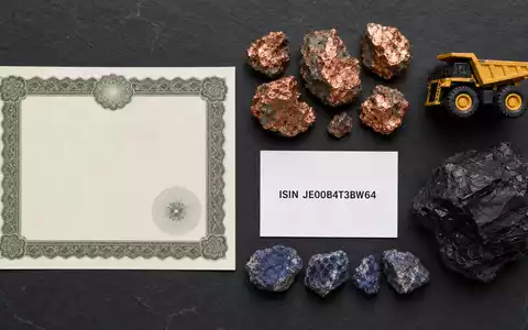 Flatlay mit Aktienzertifikat, ISIN-Karte und Rohstoffproben repräsentiert die Anlage in Glencore plc, JE00B4T3BW64 - Foto: THN