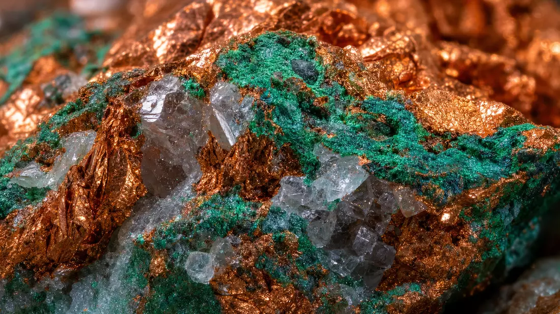 Extreme Nahaufnahme von glänzendem Kupfererz mit grünen Mineraladern und Kristallen