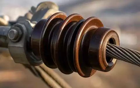 Edison International US2810201077 Makroaufnahme eines Hochspannungs-Isolators mit Stahlkabel und feiner industrieller Oberflächentextur - Foto: THN