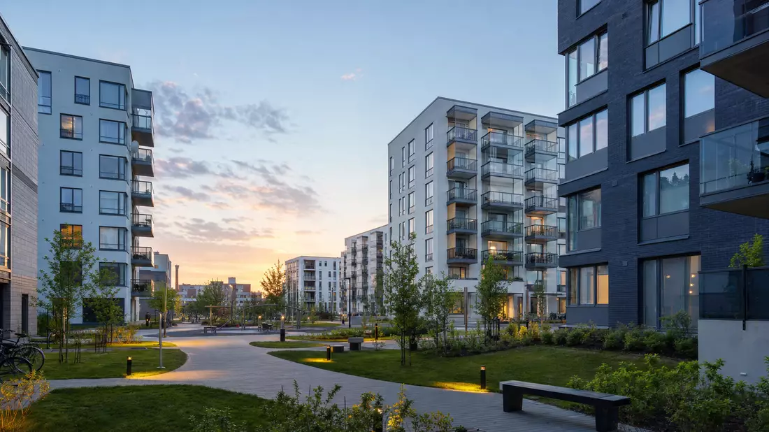Modernes Wohnhochhaus mit Grünanlagen in finnischer Stadt am Abend