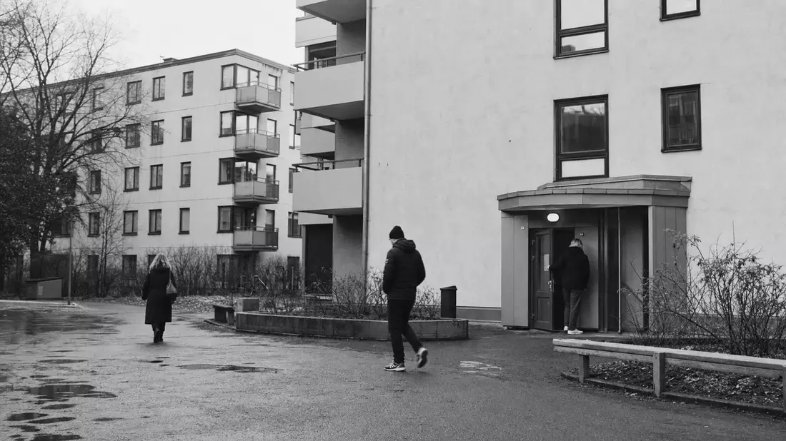 Schwarzweiß-Reportagefoto von Wohnblöcken mit Menschen im Alltag