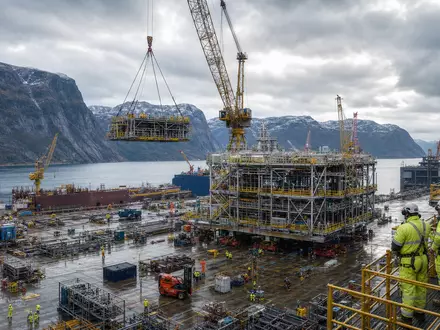 Aker Solutions ASA NO0010716582 zeigt fotorealistisch eine norwegische Offshore-Fertigungswerft mit Kränen und Modulen am Fjord - Foto: THN
