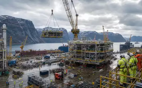 Aker Solutions ASA NO0010716582 zeigt fotorealistisch eine norwegische Offshore-Fertigungswerft mit Kränen und Modulen am Fjord - Foto: THN