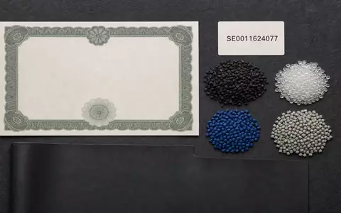 Flatlay mit Aktienzertifikat, ISIN-Karte SE0011624077 und Kautschukgranulat, symbolisch für Hexpol AB und die Branche - Foto: THN