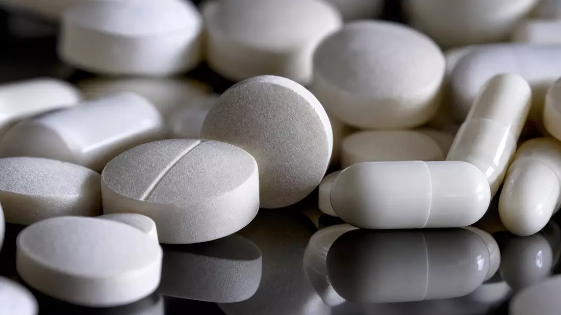 Makroaufnahme von weißen unbeschrifteten Tabletten und Kapseln mit dramatischem Licht