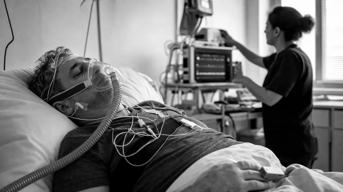 Schwarzweiß-Reportagefoto eines Patienten mit Atemmaske im Schlaflabor