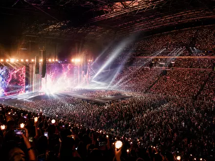 CTS Eventim DE0005470306 zeigt eine vollbesetzte Indoor-Arena mit farbenfrohem Bühnenspektakel und jubelndem Publikum - Foto: THN