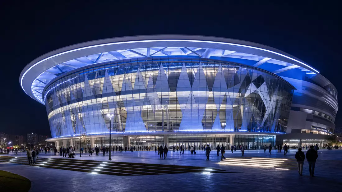 Architekturvisualisierung einer modernen Mehrzweckarena mit geschwungenem Dach bei Nacht