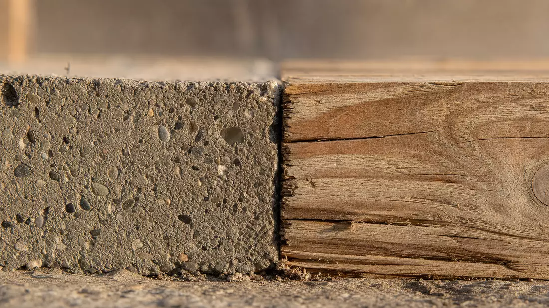 Extreme Nahaufnahme von rauem Beton und Holzmaserung im warmen seitlichen Licht