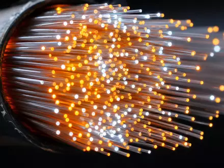 Digital Realty Trust Makroaufnahme leuchtender Glasfaser Kabel Enden als abstrakte Lichtpunkte vor Dunkel US2538681030 - Foto: THN