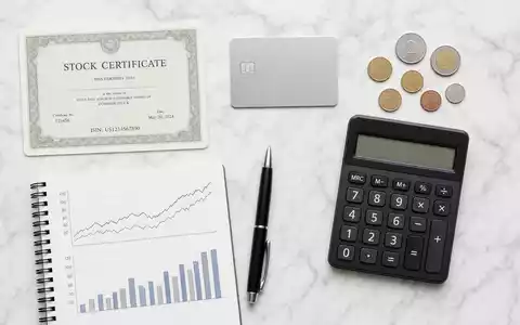 Discover Financial US2547091080 Flatlay mit Aktienzertifikat ISIN-Karte Kreditkarte Münzen Taschenrechner und Finanzdiagrammen auf Marmor - Foto: THN