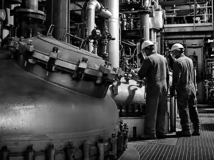 Evonik Industries DE000EVNK013 in einer dokumentarischen Schwarzweiß-Reportage von Arbeitern an industriellen Chemikalienbehältern - Foto: THN