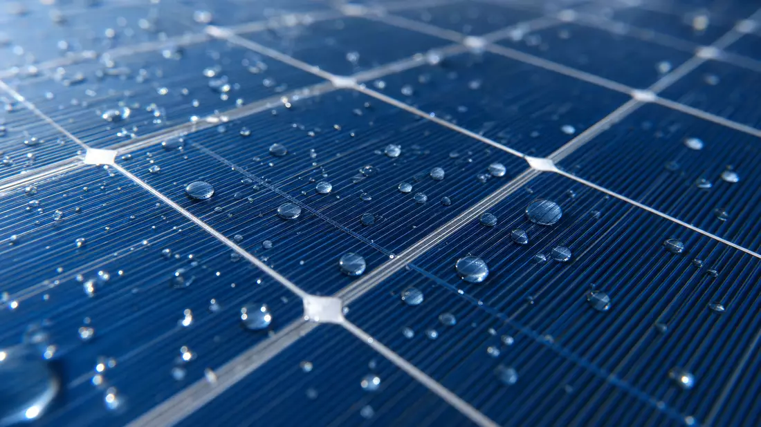 Makroaufnahme einer Solarzelle mit Wassertropfen und feinen Gitterlinien