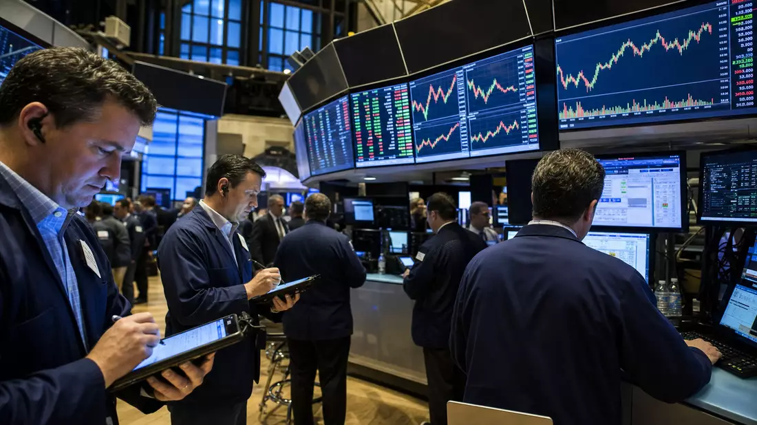 Trader an der NYSE vor Bildschirmen mit Aktiencharts der Bekleidungsbranche