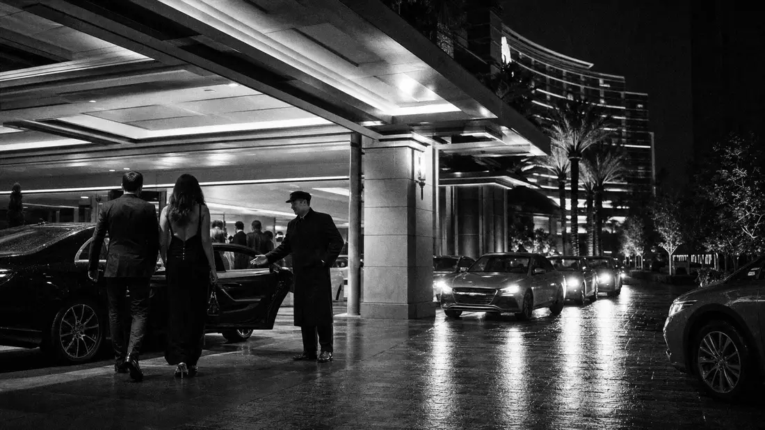 Schwarzweiß-Reportagefoto vom nächtlichen Eingang eines Resort-Hotels mit Valet-Service