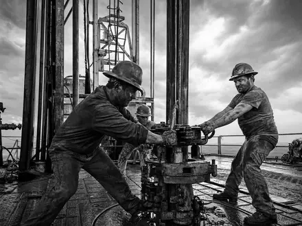 Devon Energy US25179M1036 Schwarzweiß-Reportage von Arbeitern auf einer Öl-Bohrplattform bei stürmischem Wetter - Foto: THN