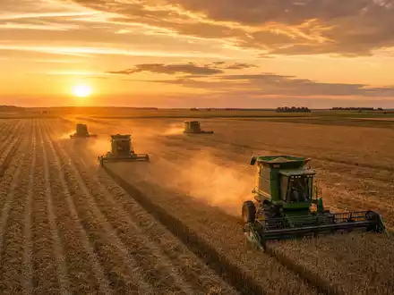 Deere & Co. Mähdrescher ernten goldene Weizenfelder bei Sonnenuntergang, ISIN US24419L1061 Maschinenbau Landmaschinen - Foto: THN