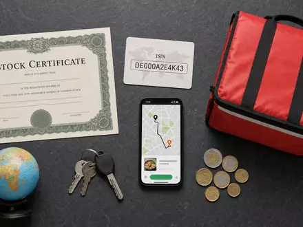 Delivery Hero SE Flatlay mit ISIN-Karte DE000A2E4K43, Aktienzertifikat und Liefertasche als Branchenutensilien - Foto: THN