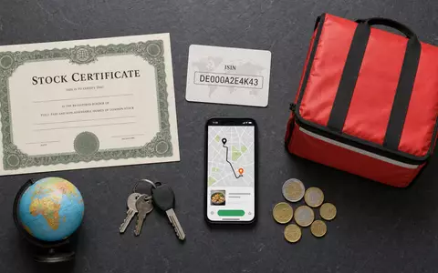 Delivery Hero SE Flatlay mit ISIN-Karte DE000A2E4K43, Aktienzertifikat und Liefertasche als Branchenutensilien - Foto: THN