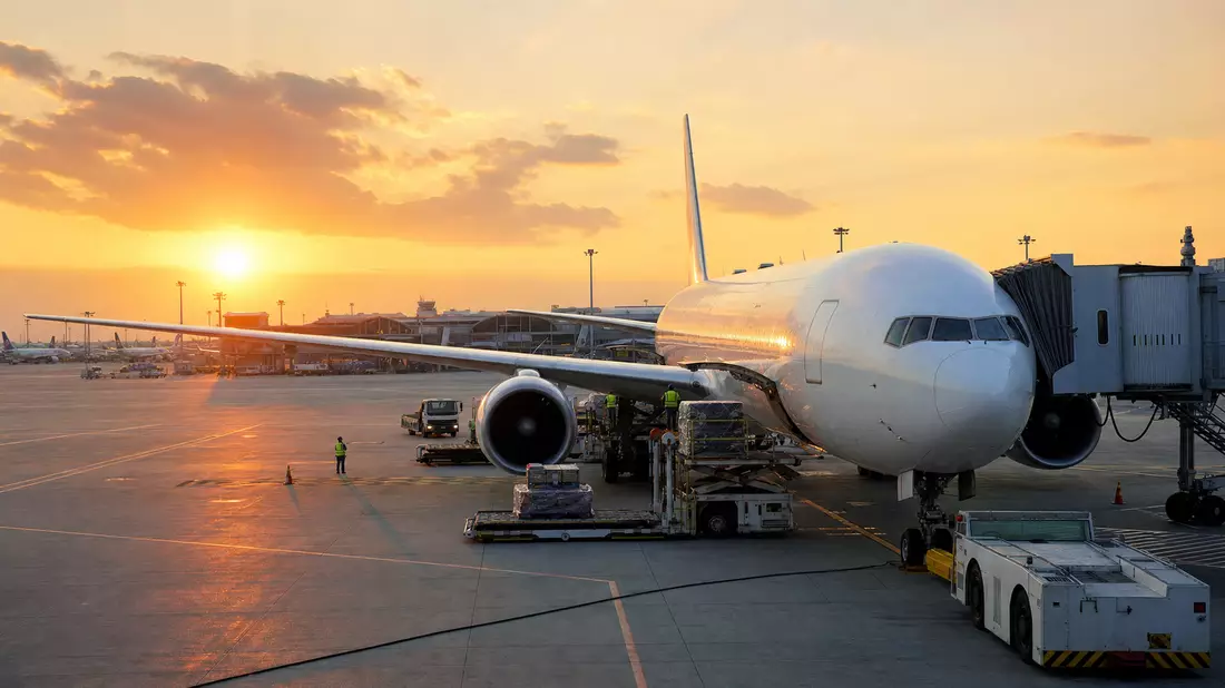 Fotorealistisches Passagierflugzeug auf Flughafen-Vorfeld bei Sonnenaufgang mit Bodenabfertigung