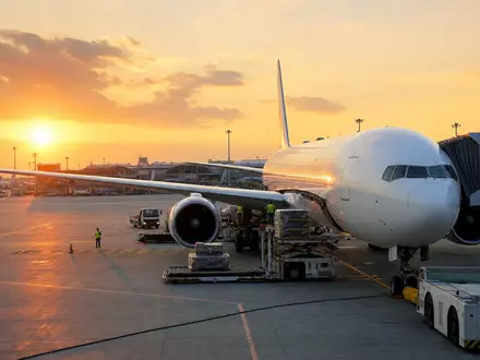 Delta Air Lines Inc. Passagierflugzeug beim Sonnenaufgang am Gate mit Bodenabfertigung, ISIN US2473617023 - Foto: THN