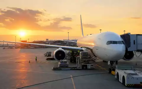 Delta Air Lines Inc. Passagierflugzeug beim Sonnenaufgang am Gate mit Bodenabfertigung, ISIN US2473617023 - Foto: THN