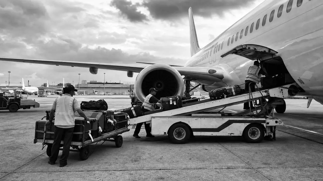 Schwarzweiß-Reportagefoto von Gepäckverladung an einem Passagierflugzeug