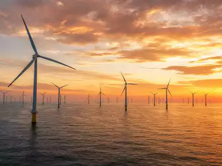 Energiekontor AG Offshore-Windpark DE0005313506 bei dramatischem goldenem Sonnenuntergang über dem ruhigen Meer - Foto: THN
