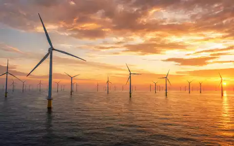 Energiekontor AG Offshore-Windpark DE0005313506 bei dramatischem goldenem Sonnenuntergang über dem ruhigen Meer - Foto: THN