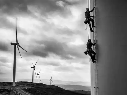 Energiekontor AG DE0005313506 zeigt Techniker in Schwarz-Weiß beim Klettern an einer Windkraftanlage - Foto: THN