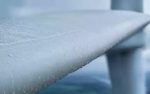 Energiekontor AG DE0005313506 Makro-Detailaufnahme eines weißen Rotorblatts mit vielen glitzernden Wassertropfen darauf - Foto: THN