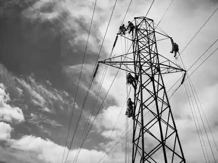 Entergy Corp. zeigt Elektriker beim Erklimmen eines Hochspannungsturms in einer dokumentarischen Schwarzweißaufnahme, ISIN US29364G1031 - Foto: THN