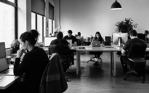 The Sage Group plc (GB00B8C37574) in dokumentarischer Schwarzweiß-Reportage mit Angestellten in einem Softwareunternehmen-Großraumbüro - Foto: THN