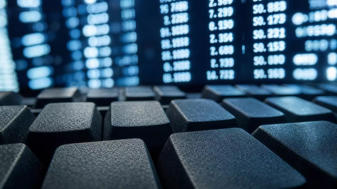 Makroaufnahme einer Tastatur mit Zahlen und Softwarecode im unscharfen Hintergrund