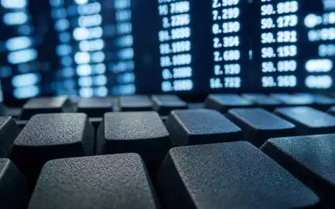 The Sage Group plc (GB00B8C37574) zeigt eine Makroaufnahme einer Computertastatur mit unscharfem Bildschirmcode im Hintergrund - Foto: THN