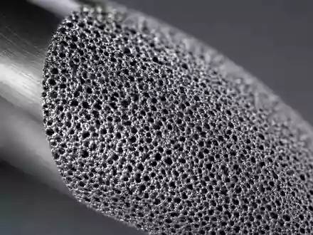 Zimmer Biomet US98956P1021 zeigt Makroaufnahme der porösen Titanoberfläche eines orthopädischen Implantats in dramatischem Streiflicht - Foto: THN